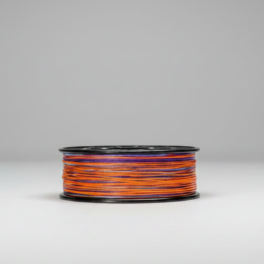Spool of orange and blue thread on a white background